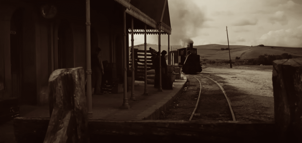 Locomotora acercándose a la estación en una escena lejana de Pampa Salvaje (1966), con pasajeros esperando